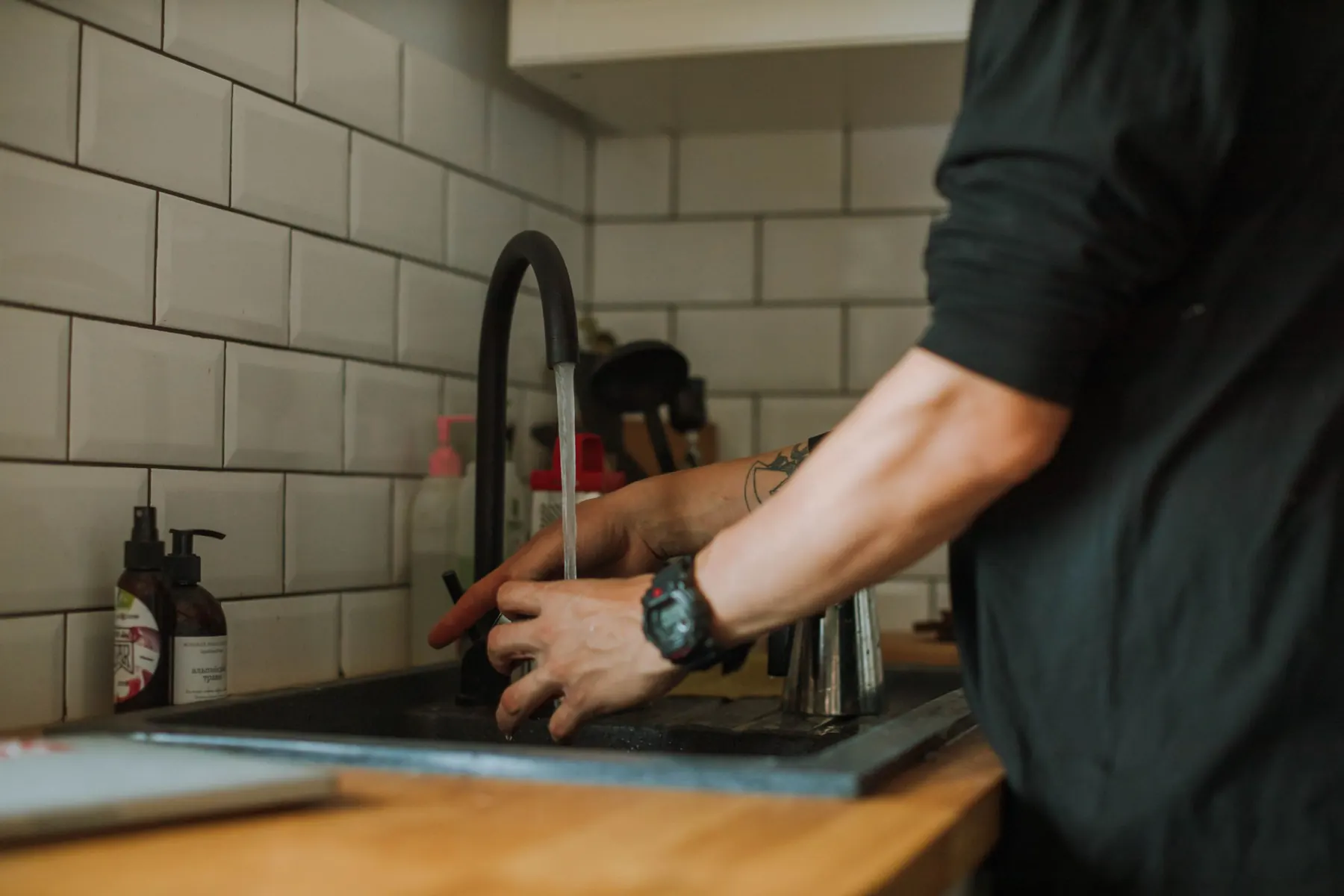 Hands working at a kitchen sink tap